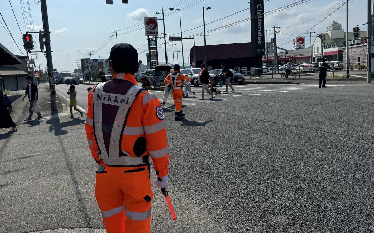 横断歩道で歩行者を誘導する警備スタッフ